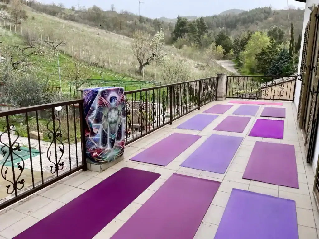 The large outdoor terrace of the La Vita Sukha villa set up for a yoga class with 12 purple yoga mats prepared for students